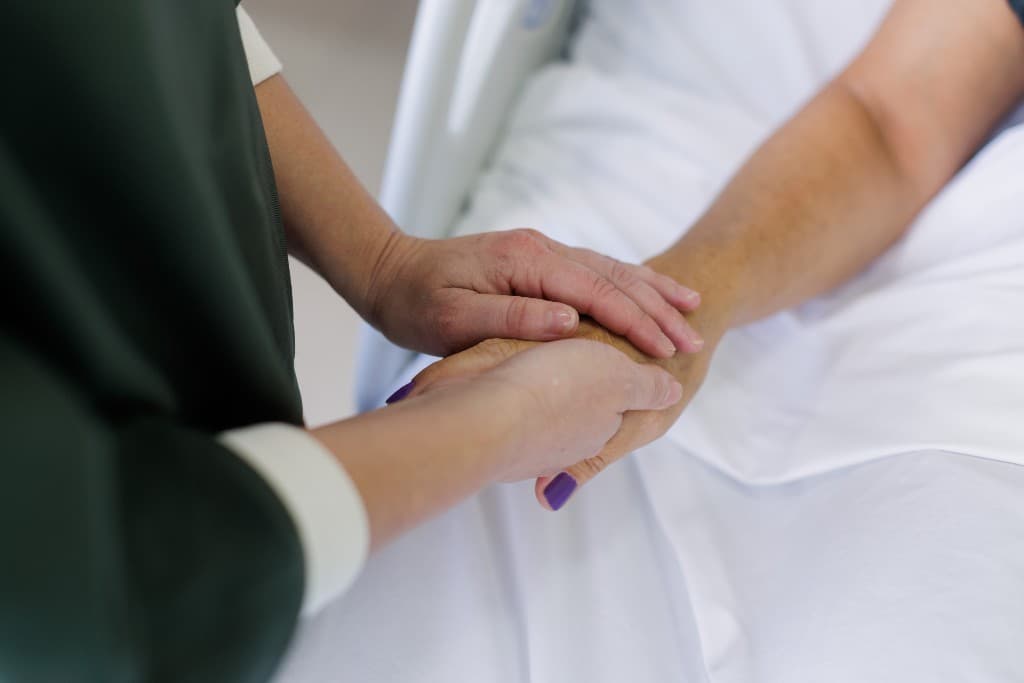 Mãos de médico segurando mãos de paciente